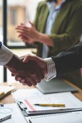 Two confident businessmen holding hands during a meeting in the office, success, management, colleagues standing and applauding, wishing congratulations. Alliance concept.