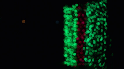 Light green bokeh against dark background at night, green bokeh representing.