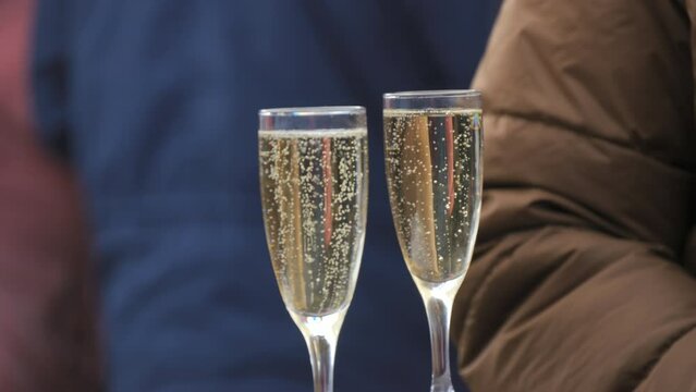 Two glasses of champagne at a street winter food court bubbles in slow motion