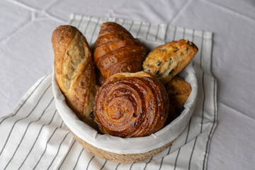 Charming tableau of a basket filled with French pastries on a table. Croissants and puff pastry...