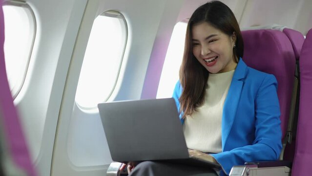 Passenger, confident Asian businesswoman sitting on airplane working on laptop computer with simulator space using wireless connection on successful airplane, flying in first class.