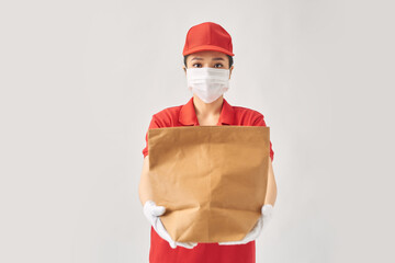 happy smiling delivery woman in red uniform with takeaway food in paper bag over white background