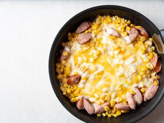 Stir-fried sausage and corn with cheese in a pan
