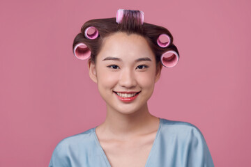 Pretty young woman in curlers smiling and looking at the camera