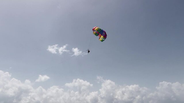 Panor&aacute;mico de un paraca&iacute;das con los colores LGBTQ+ volando sobre el mar.