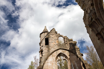 Part of the ruined pediment, an arched figured opening and the conical roof of the tower of the...