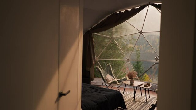 Modern glamping accommodation for tourists. Semi lit premise with decorative elements for living in country house. Sun rays fall on interior items