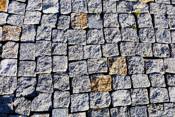 Top view on stone road close up. Old pavement of granite. Brown square cobblestone sidewalk. Mock up or vintage grunge texture.