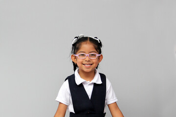 4 year old Latina brunette girl dressed in school uniform looks very happy to go on vacation or...