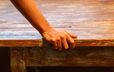 The girl's hand rests on an old wooden table. Close-up