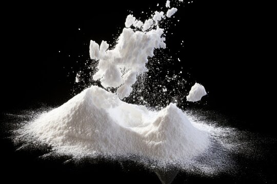 A pile of white powder on a black background. This image can be used to depict substances, drugs, or chemical elements