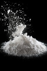 A pile of white powder on a black background. Perfect for illustrating concepts related to substance abuse, drugs, illegal substances, addiction, and crime. - obrazy, fototapety, plakaty