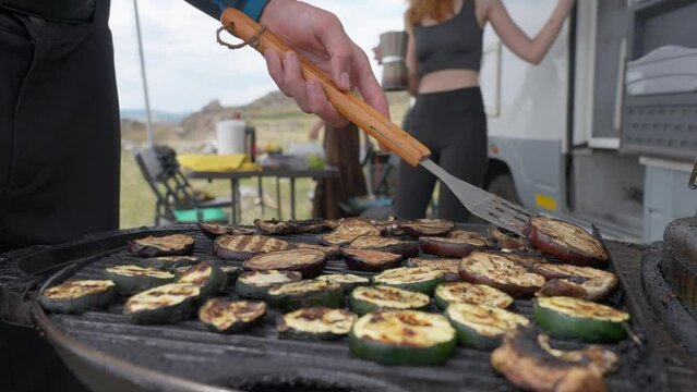 Grilling vegetables zucchini on portable grill near RV camping, young women