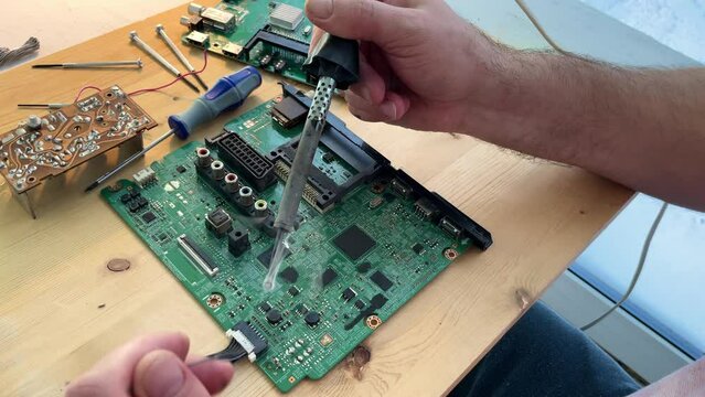 Close up Soldering a micro chip processor with iron tool on a green circuit boad. Electroncs service technology and macro computer concept background.