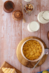 cornflakes in a bowl, milk in a glass and a jug next to it. Brea