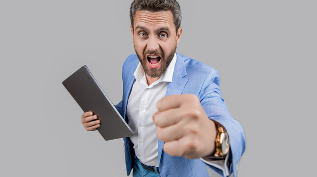 Business boss man feel anger and aggression. Anger management. Angry and aggressive man threatening with fist. Angry businessman isolated on grey. Businessman hold laptop and threatening with fist