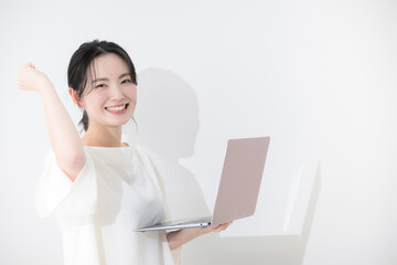 パソコン持ってガッツポーズの若いかわいい女性のビジネスイメージ