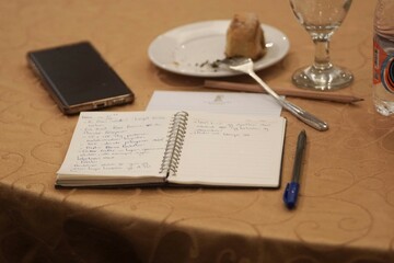 Books, pens, cellphones and cakes lay on the table. Just above the shot of the object on the table