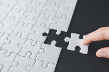 Fototapeta premium Hand put the last piece of jigsaw puzzle to complete the mission, Business solutions, success and strategy concept, The solution includes completing the mission.