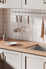 A bright beige-toned kitchen interior with sunlight 
coming through the window.