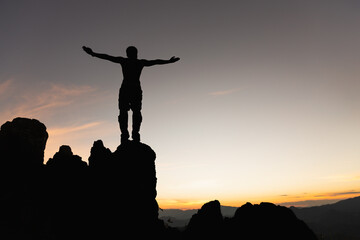 silhouette of man rising hands at peak of mountains.  Successfully achieving your goal. Success Business Leadership,  Successful person has achieving.