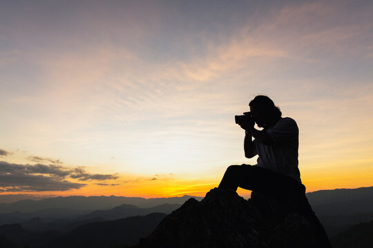 Silhouette of a photographer on top of a mountain at sunset