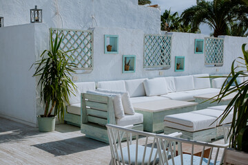 Exterior of a white resort terrace with white ceramic walls, and flowers in pots standing in blue,...