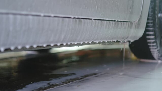 Auto detailer blankets car in luxurious foam, creating a captivating scene. The vehicle, immersed in suds, showcasing thorough cleansing artistry.