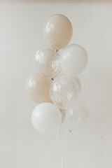 White, beige and transparent balloons with polka dots. White background.