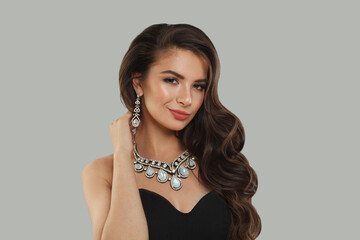 Gorgeous glamorous woman jewelry model with diamonds posing on gray background