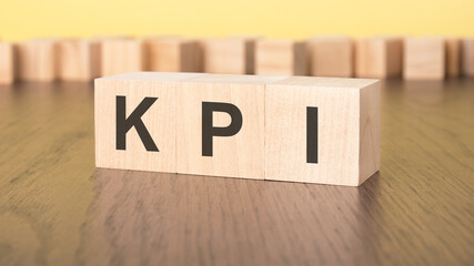 three wooden cubes on a yellow background, with the abbreviation KPI - Key Performance Indicators