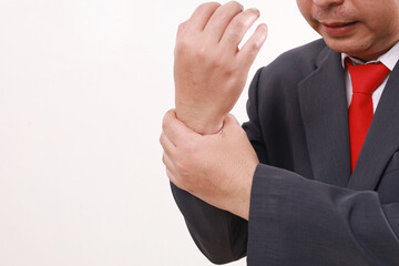 Close up photo of Asian businessman standing while holding his cramp wrist. Isolated on white