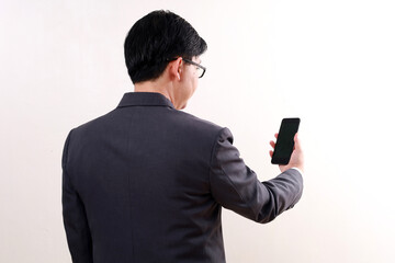 Back view of asian businessman standing while holding a cell phone. Isolated on white
