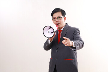 Angry asian businessman shouting using megaphone while pointing at you. Isolated on white