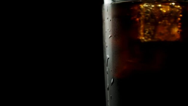 Glass with whiskey and soda and ice cubes that spin on a black background