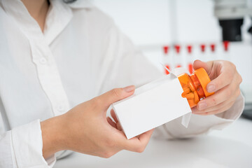 doctor demonstrates a bottle of pills in a cardboard box without text
