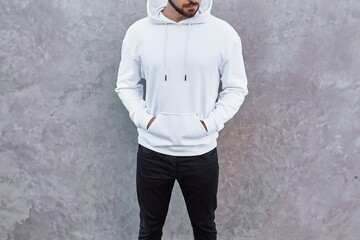 A mock-up template of a white hoodie worn by a man. A design concept for print and branding. A...