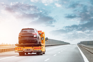 A tow truck with a broken car on a road. Tow truck transporting a car on the highway. Car service...