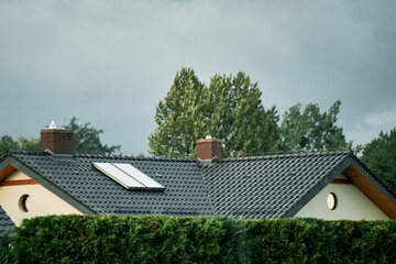 A modern house with a solar water heating system on the roof. Water solar collector on the roof of...