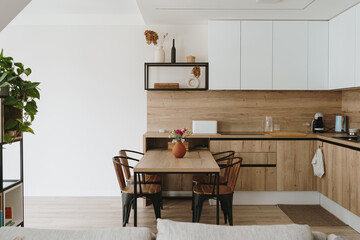 Modern bright kitchen interior with white furniture and wooden dining table - obrazy, fototapety, plakaty