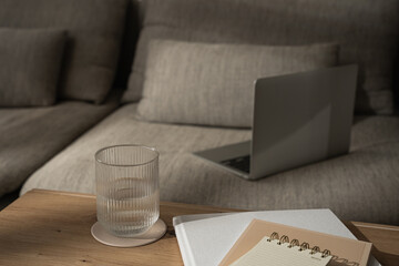 Work at home concept. Laptop computer on comfortable sofa. Notebooks, glass of water on wooden...