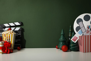 Clapperboard, popcorn, Christmas decorations and box with movie supplies on dark green background,...