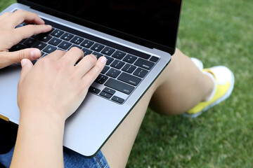 A girl works on a laptop on the grass