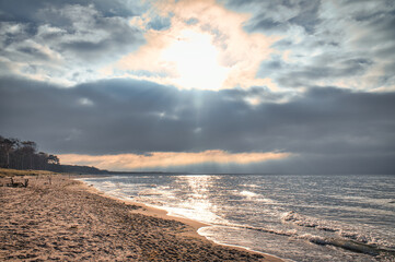 Sunset on the west beach on the Baltic Sea. Waves, beach, cloudy sky and sunshine