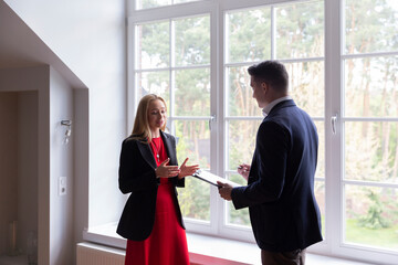 Real estate agent helps blonde businesswoman with choosing available house. Potential customer...