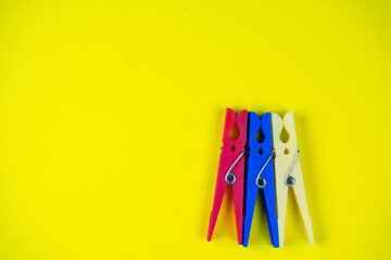 several multi-colored clothespins on a yellow background. space for text