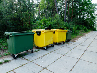 Yellow and green big wheelie bins in a street ready for collection. Waste management in a city. Rubbish collection point in town.