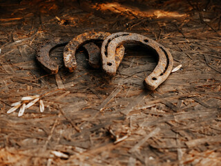 Rusty metal horse shoe on a dirty wooden surface. Symbol of luck.