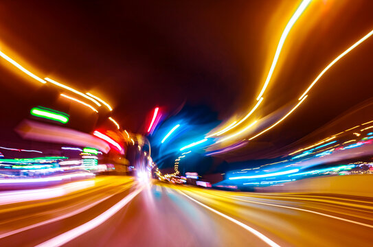 City colorful night lights perspective blurred by high speed of the car. A streak of light, trails.