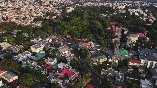 An aerial view of Dehradun, an Indian city during sunrise or sunset, with cloudy weather and rows of residential houses surrounded with greenery.